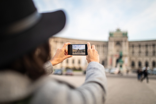 City Discovery Game Vienna City Discovery Game - woman taking photos of famous square in Vienna,focus on smart phone